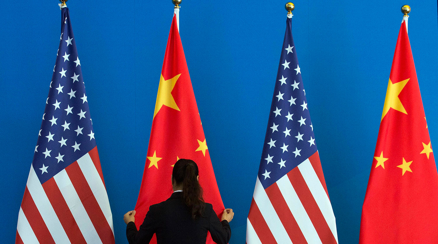 A Chinese woman adjusts a Chinese national flag next to U.S. national flags before a Strategic Dialogue expanded meeting, part of the U.S.-China Strategic and Economic Dialogue (S&ED) in Beijing