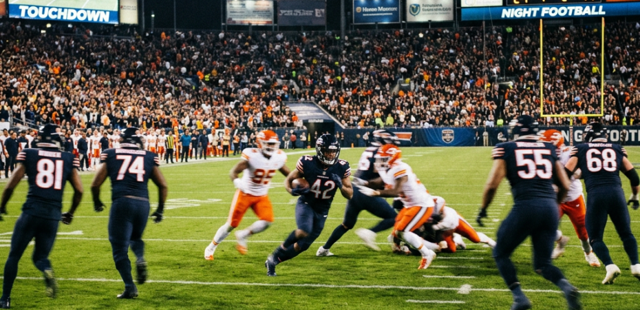 Football player running with the ball as opponents try to tackle him at night game